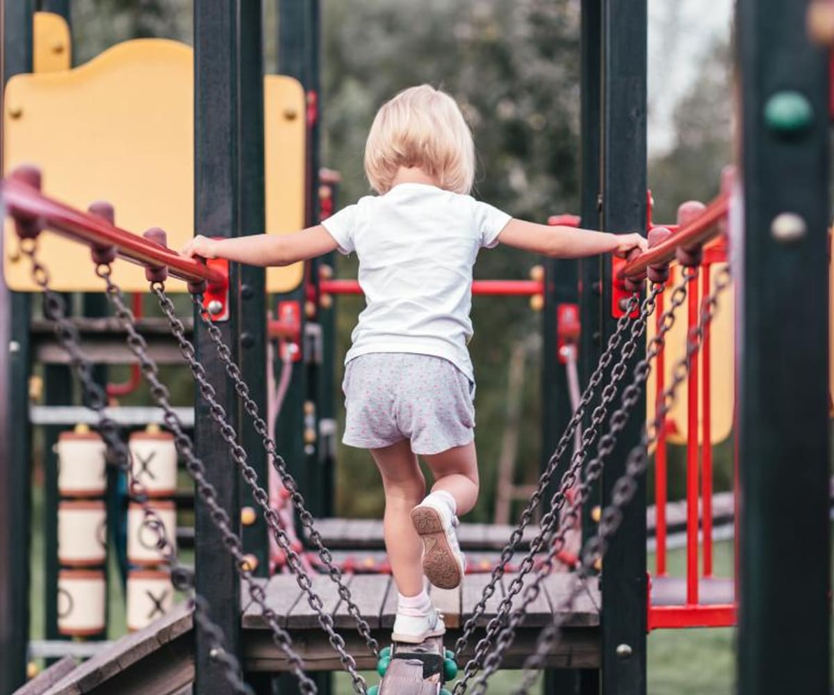 A young child climbing across a playground frame at an outdoor attraction